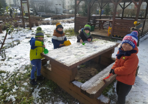 chłopcy sprzątają śnieg łopatkami