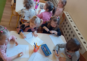 Dzieci przy stolikach wykonują pracę grafomotoryczną