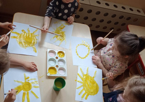 Dzieci samodzielnie malują farbami słońce