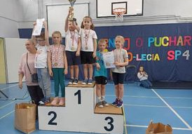 Dzieci stoją na podium z medalem i dyplomem
