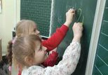 Dwie dziewczynki piszą kredą na tablicy