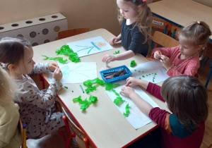 Dzieci przy stolikach wykonują pracę plastyczną - kwiatek w doniczce