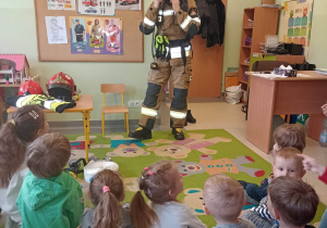 Pan strażak pokazuje dzieciom szybki sposób ubierania się w specjalistyczny strój
