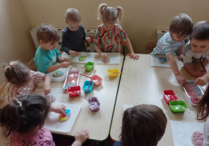 Dzieci dekorują ciastko w kształcie wielkanocnej pisanki