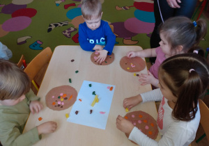 Dzieci tworzą swoja pizzę lepiąc w plasteliny dodatki takie jak: szynka, pieczarki, papryka itp.