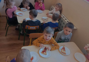 Dzieci jedzą tradycyjne danie włoskie - pizzę Margheritę
