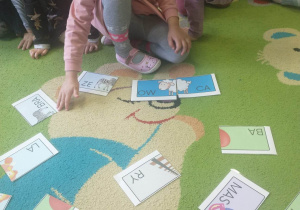 dzieci siedzą na dywanie, dzieci odczytują sylaby