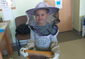 chłopiec pozuje do zdjęcia w kapeluszu pszczelarskim