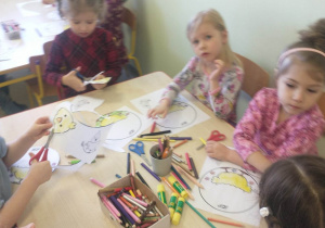 dzieci malują, wycinają nożyczkami kurczaczka przy stoliku