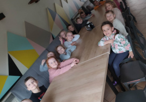 dzieci siedzą przy stole i czekają na pizze