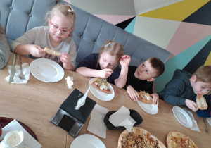 dzieci jedzą pizzę z sosem