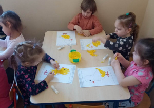 Dzieci wypełniają kontury kurczaczka żółtą bibułą