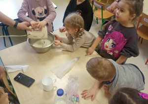 dzieci wraz z nauczycielką miksują ciasto na babeczki
