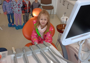 Dziewczynka z uśmiechem i bez strachu siada na fotelu dentystycznym