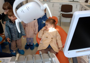 Dziewczynka obserwuje sprzęty i urządzenia dentystyczne potrzebne do leczenia zębów