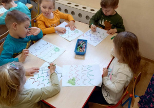 Dzieci wykonują pracę grafomotoryczną - rysują po śladzie skoki żaby