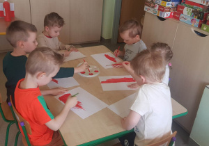dzieci siedzą przy stoliku, dzieci malują flagę Polski