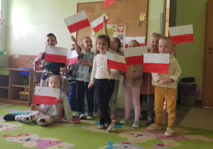 dzieci pozują do zdjecia z własnoręcznie wykonaną- flagą Polski