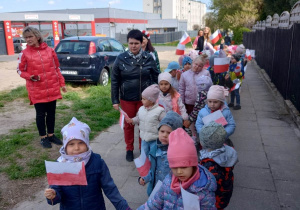 Dzieci wraz z własnoręcznie zrobionymi flagami spacerują ulicami osiedla