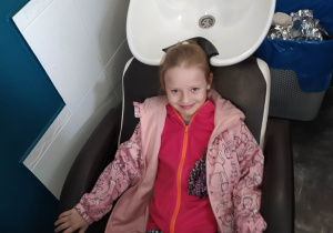 dziewczynka siedzi na fotelu przy myjce do włosów