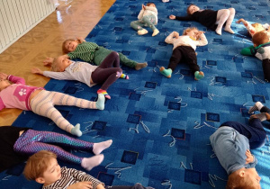 Dzieci słuchają muzyki relaksacyjnej leżąc na dywanie