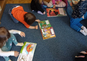 Dzieci oglądają książeczki na dywanie