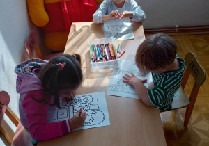 Dzieci przy stolikach kolorują obrazki
