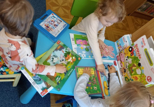 Dzieci oglądają książeczki przy stolikach w czytelni