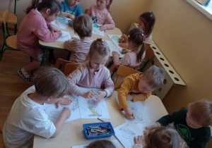 Dzieci wypełniają kontury Warszwskiej Syrenki kredkami