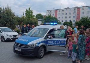 Dzieci wraz z rodzicami oglądają radiowóz policyjny