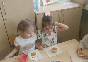 dziewczynki siedzą przy stoliku i dekorują muffinki