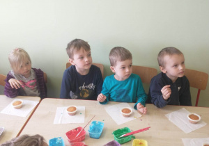 dzieci siedzą przy stoliku, dzieci dekorują muffinki