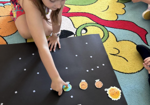 dziewczynka pokazuje planety na tablicy