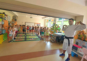 Pan Łukasz wraz z dziećmi ćwiczy - pokazuje podstawowe ruchy i komendy w karate