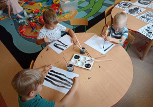 Chłopcy malują obraz z wykorzystaniem czarnych linii