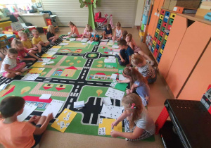 Dzieci siedzą na dywanie układają litery.