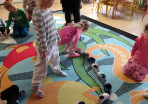 Dzieci ustawiają kolejno po sobie buty, sprawdzając który jako pierwszy przekroczy próg