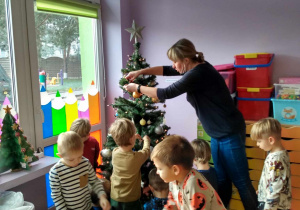 Dzieci z radością ubierają świąteczne drzewko