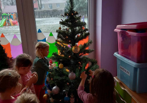 Dziewczynki zawieszają bombki na świątecznym drzewku