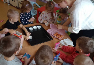 Dzieci układają foremki do babeczek na blasze do pieczenia