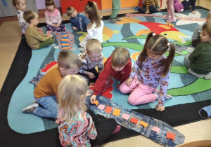 Dzieci w grupach układają kwadraty na szalu według określonego rytmu