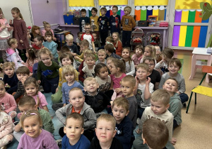 Dzieci siedzą na dywanie czekając na pokaz różnorodnych rodzajów tańca w wykonaniu Poli