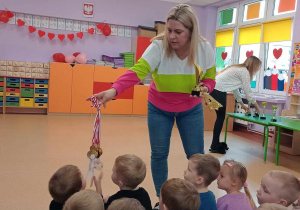 Nauczycielka pokazuje medale, które Pola zdobyła na różnych pokazach tańca w Polsce i na świecie