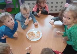 Dzieci jedzą przy stolikach faworki