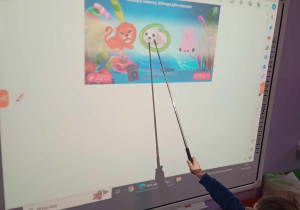 Chłopiec udziela prawidłowej odpowiedzi zaznaczając odpowiedni rysunek na tablicy multimedialnej