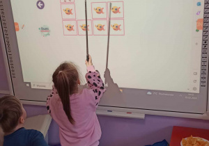 Dziewczynka gra na tablicy multimedialnej w grę memory obrazkowe