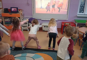 Dzieci tańczą naśladując ruchy animatora na tablicy multimedialnej