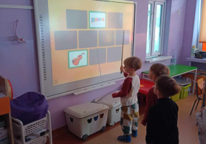 Chłopiec rozpoznaje instrument na tablicy multimedialnej i szuka drugiego takiego samego obrazka