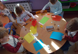 Dzieci wycinają różne kształty z kolorowego papieru i ozdabiają swój instrument