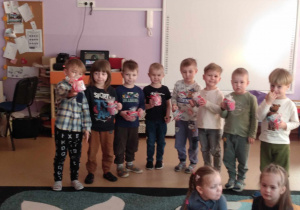 Chłopcy trzymają w rękach prezent dla dziewczynek - kubek ze słodyczami